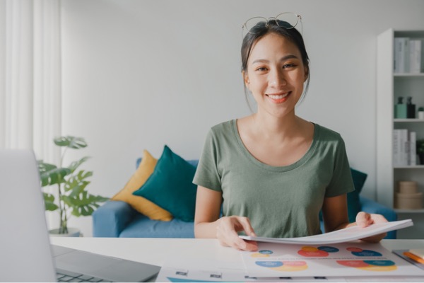 Woman at home with papers in hand.